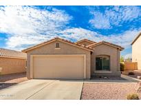 Tan house with a two-car garage and desert landscaping at 7244 S Sunrise Way, Buckeye, AZ 85326