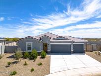 Single-story house with gray exterior, three-car garage, and desert landscaping at 3422 N Cinnabar Pl, Casa Grande, AZ 85122