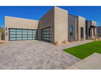 Modern home exterior with a three-car garage and landscaped front yard at 5740 E Moura Dr, Cave Creek, AZ 85331