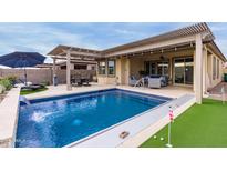 Inviting backyard pool with a covered patio and putting green at 17937 W Cedarwood Ln, Goodyear, AZ 85338