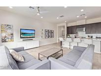 Open-concept living room featuring stylish gray sofas, modern entertainment center, and kitchen with bar seating at 23386 N 73Rd Way, Scottsdale, AZ 85255