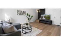 Bright living room with hardwood floors, gray sofa, and glass coffee table at 5238 N 42Nd Ln, Phoenix, AZ 85019