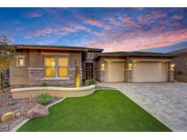 Beautiful home with a three-car garage, stone accents, manicured lawn, and desert landscaping against a vivid sky at 32722 N 132Nd Ln, Peoria, AZ 85383