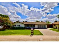 Charming single-story home with a well-manicured lawn, brick driveway, and modern garage door at 615 E Winter Dr, Phoenix, AZ 85020