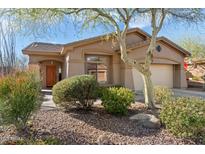 One-story house with tan exterior, landscaped yard, and two-car garage at 2327 W Firethorn Way, Anthem, AZ 85086