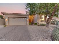 Tan house with a three-car garage and landscaped front yard at 35167 N 92Nd Pl, Scottsdale, AZ 85262