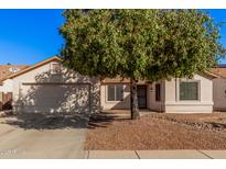 Single-story home with two-car garage and mature tree in front yard at 14352 W Lamoille Dr, Surprise, AZ 85374