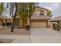 Two-story house with beige exterior, two-car garage, and landscaping at 17427 W Rock Wren Ct, Goodyear, AZ 85338