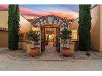 Elegant home exterior featuring a grand arched entryway, lush landscaping, and a gated courtyard at 37018 N Tree Lined Trl, Carefree, AZ 85377