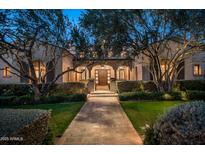 Elegant home with a stucco exterior, arched entryway, and manicured landscaping at 10320 E Mountain Spring Rd, Scottsdale, AZ 85255