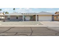 Gray brick ranch house with white pergola and attached garage at 17635 N Buntline Dr, Sun City West, AZ 85375