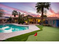 Beautiful backyard featuring a sparkling pool, putting green, and outdoor kitchen, perfect for entertaining at 2131 W Ironwood Dr, Chandler, AZ 85224