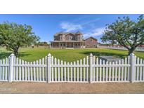 Charming two-story home features a well-maintained lawn, mature trees, and a classic white picket fence at 424 E Lehi Rd, Mesa, AZ 85203