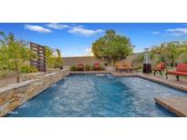 Inviting backyard pool with a stone waterfall feature and comfortable lounge seating at 5424 N 186Th Dr, Litchfield Park, AZ 85340