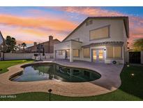 Stunning backyard oasis with a kidney-shaped pool, outdoor kitchen, and landscape lighting at 6270 W Rose Garden Ln, Glendale, AZ 85308