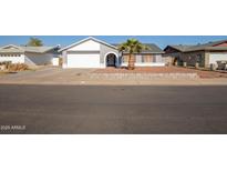 Single-story house with a gray exterior, white garage door, and a palm tree in the front yard at 7210 W Pasadena Ave, Glendale, AZ 85303