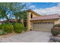 Tan two-story home with a tile roof, two-car garage, and nicely landscaped yard at 7846 E Mackenzie Dr, Scottsdale, AZ 85251