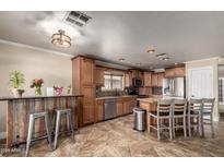 Well-lit kitchen with stainless steel appliances, wooden cabinets and island with breakfast bar at 11346 E Renata Ave, Mesa, AZ 85212