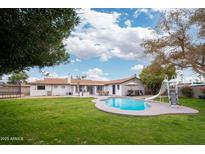 Inviting backyard oasis featuring a sparkling pool, grassy lawn, and patio entertaining area at 1624 W Lawrence Rd, Phoenix, AZ 85015