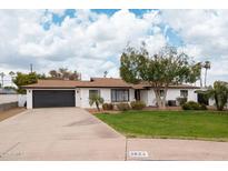 Single-story home with a landscaped yard, driveway, and attached garage at 1624 W Lawrence Rd, Phoenix, AZ 85015