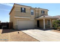 Two story house with tan exterior, two car garage, and covered entryway at 25527 W Burgess Ln, Buckeye, AZ 85326