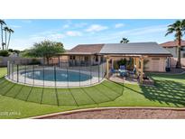 Inviting backyard oasis with a sparkling pool, solar panels, and a relaxing patio area at 859 N 54Th Cir, Mesa, AZ 85205