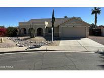 Tan one-story house with arched entryway, two-car garage, and desert landscaping at 4963 E Hobart St, Mesa, AZ 85205