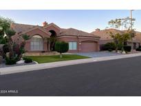 Charming single-story home featuring a neutral color, tile roof, manicured lawn, and two-car garage at 9672 E Davenport Dr, Scottsdale, AZ 85260