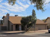 Tan two-story house with a brown roof, two-car garage, and mature landscaping at 1305 W Isabella Ave, Mesa, AZ 85202