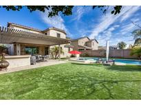 Sprawling backyard with a covered patio, pool, artificial turf, and outdoor seating, creating a serene and inviting outdoor space at 3933 E Alfalfa Dr, Gilbert, AZ 85298