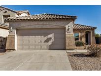 Tan house with tile roof, two-car garage, and desert landscaping at 42788 W Martie Lynn Rd, Maricopa, AZ 85138