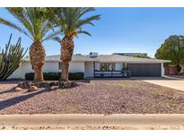 Mid-century modern home with a landscaped front yard and two palm trees at 7513 E Minnezona Ave, Scottsdale, AZ 85251