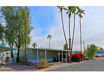 Mobile home with covered porch, landscaped yard, and mature palm trees at 9501 E Broadway Rd # 140, Mesa, AZ 85208