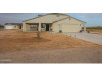 Tan house with covered porch, attached garage, and landscaped yard at 10428 S 294Th Ave, Palo Verde, AZ 85343