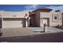 Tan two-car garage stucco home with a Spanish-style tile roof at 26409 S Moonshadow Dr, Sun Lakes, AZ 85248