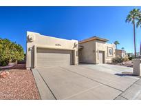 Front view of a tan house with a two-car garage and desert landscaping at 26409 S Moonshadow Dr, Sun Lakes, AZ 85248