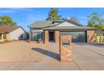 Brick ranch home with gray exterior, black garage door, and landscaped yard at 5344 W Desert Hills Dr, Glendale, AZ 85304