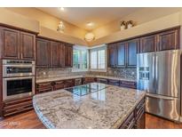 Gourmet kitchen boasts dark wood cabinetry, granite countertops, and stainless steel appliances at 4410 E Robin Ln, Phoenix, AZ 85050