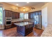 Gourmet kitchen boasts dark wood cabinetry, granite countertops, and stainless steel appliances at 4410 E Robin Ln, Phoenix, AZ 85050