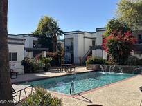 Community pool with waterfall feature and surrounding landscaping at 740 W Elm St # 119, Phoenix, AZ 85013