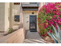 Condo building entrance with a gated entry and blooming flowers at 2315 W Union Hills Dr # 112, Phoenix, AZ 85027