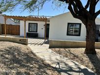 Charming single-story home featuring stucco walls, black-framed windows, and a wooden pergola for shaded outdoor seating at 4032 N 11Th Ave, Phoenix, AZ 85013