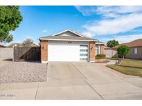 Brick home with a white garage door and well-manicured lawn at 8828 E Des Moines St, Mesa, AZ 85207