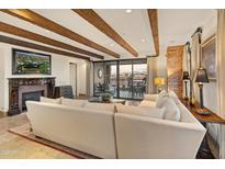 Spacious living room features exposed wood beams, fireplace, and access to a balcony with city views at 7181 E Camelback Rd # 506, Scottsdale, AZ 85251