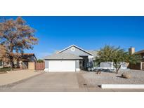 Single-story home with gray exterior, white garage door, and landscaped yard at 7710 W Aster Dr, Peoria, AZ 85381