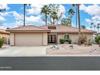 Tan house with tile roof, two-car garage, and nicely landscaped yard at 10009 E Michigan Ave, Sun Lakes, AZ 85248