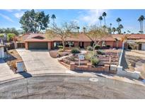 Single-story home with desert landscaping, large driveway, and attached garage at 215 E Marconi Ave, Phoenix, AZ 85022