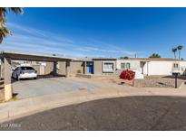 Charming single-story home featuring a carport, desert landscaping, and a vibrant blue front door at 4124 N 105Th Ln, Phoenix, AZ 85037