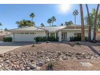 White single story home with metal roof, desert landscaping, and a two car garage at 7489 E Windrose Dr, Scottsdale, AZ 85260