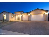 Tan three-car garage home with a paved driveway and desert landscaping at 22665 E Stacey Rd, Queen Creek, AZ 85142